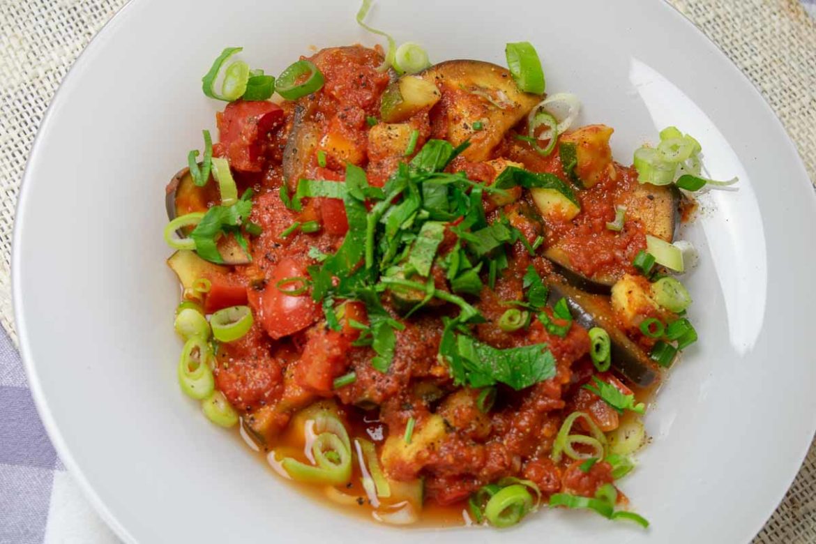 Ratatouille mit Paprika und Zucchini, serviert mit frischen Kräutern